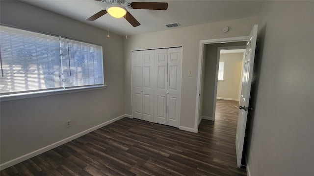 unfurnished bedroom with multiple windows, ceiling fan, a closet, and dark wood-type flooring