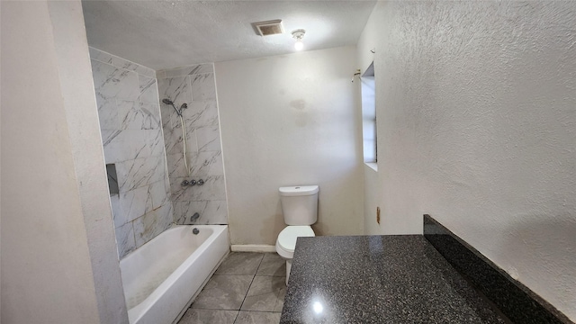 bathroom featuring tile patterned flooring, tiled shower / bath combo, and toilet