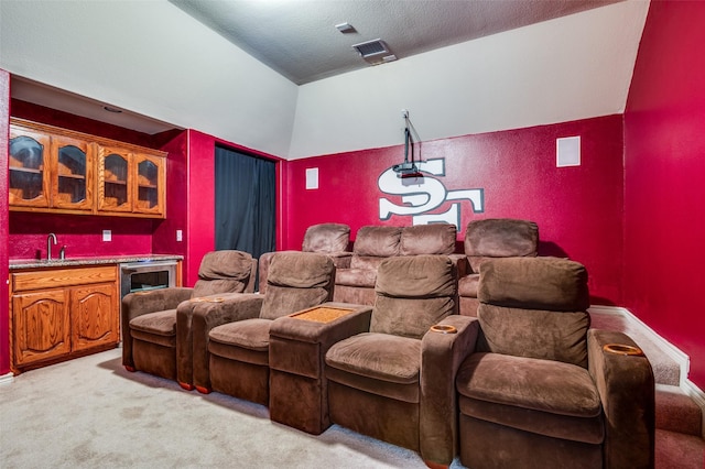 carpeted cinema room featuring indoor bar, a textured ceiling, and lofted ceiling