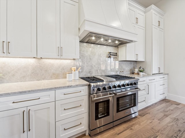 kitchen featuring white cabinetry, custom range hood, double oven range, light hardwood / wood-style flooring, and tasteful backsplash