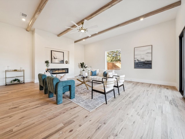 living room with ceiling fan, light hardwood / wood-style flooring, and beamed ceiling