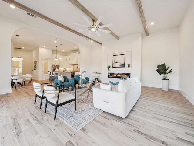 living room featuring ceiling fan, beamed ceiling, and light hardwood / wood-style flooring