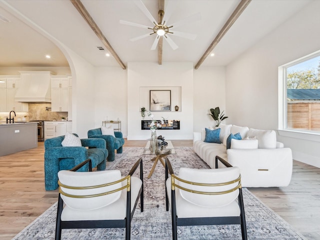 living room with beam ceiling, ceiling fan, light hardwood / wood-style floors, and sink