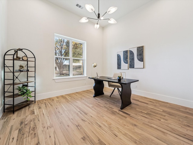 office space with light wood-type flooring and an inviting chandelier