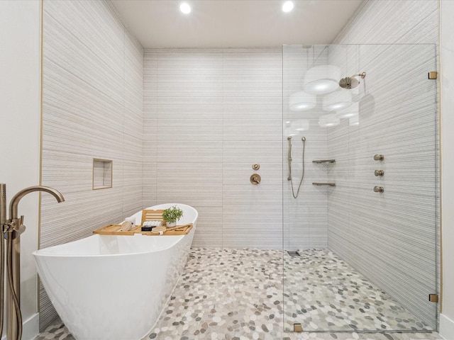 bathroom with tile walls, separate shower and tub, and sink