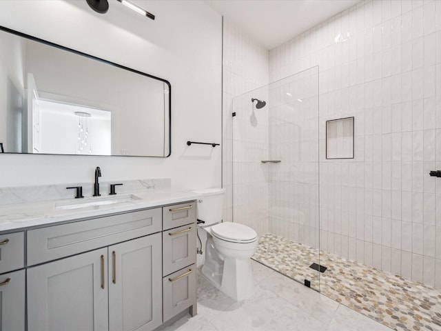 bathroom featuring a tile shower, vanity, and toilet