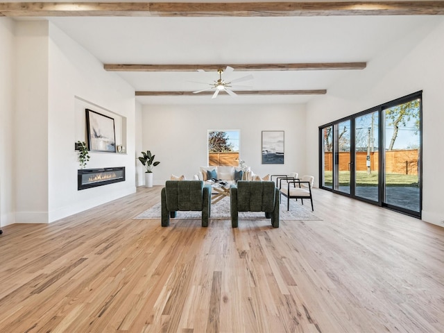 living room featuring beam ceiling, light hardwood / wood-style floors, and a healthy amount of sunlight