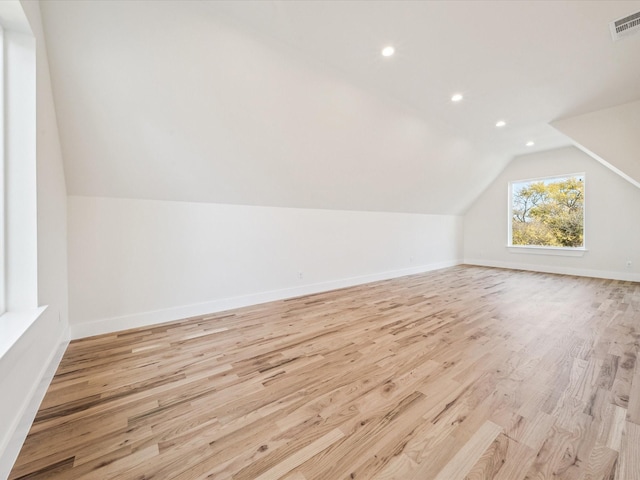 additional living space featuring vaulted ceiling and light hardwood / wood-style flooring