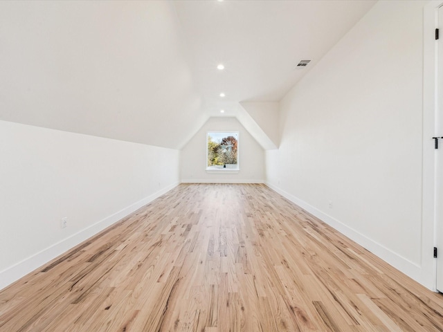 bonus room with light wood-type flooring and vaulted ceiling