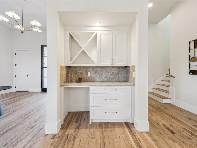 kitchen with decorative light fixtures, white cabinetry, an inviting chandelier, tasteful backsplash, and light hardwood / wood-style flooring