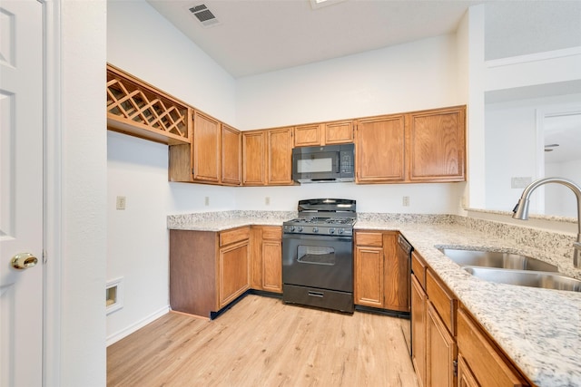 kitchen featuring black appliances, light stone countertops, sink, and light hardwood / wood-style flooring