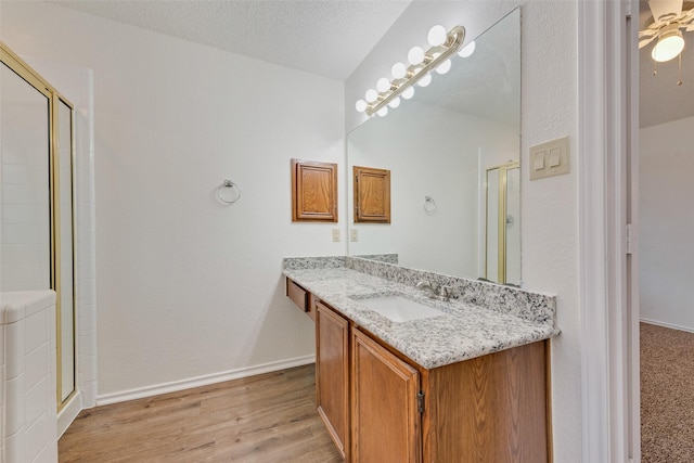 bathroom with vanity, hardwood / wood-style floors, a textured ceiling, and a shower with shower door