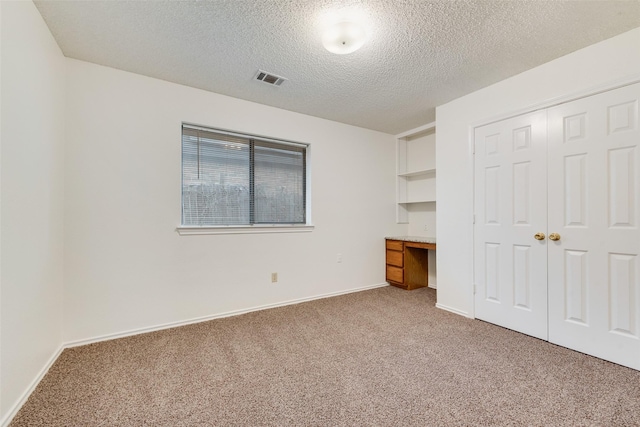 unfurnished bedroom with a closet, carpet floors, and a textured ceiling