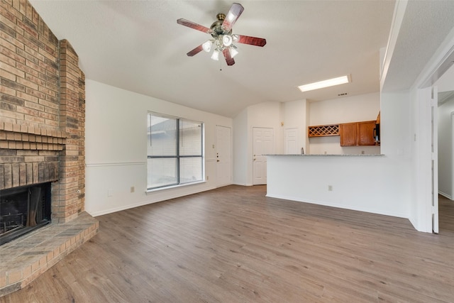 unfurnished living room featuring a textured ceiling, ceiling fan, a fireplace, hardwood / wood-style floors, and lofted ceiling