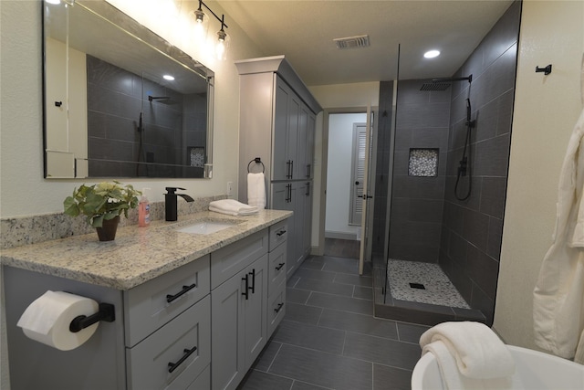 bathroom with tile patterned flooring, vanity, and a tile shower