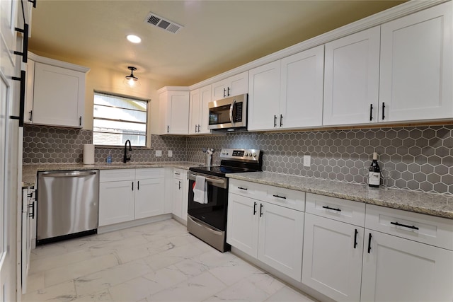 kitchen with backsplash, white cabinets, sink, light stone countertops, and appliances with stainless steel finishes