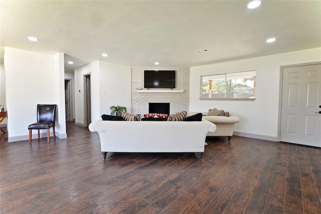 living room with dark hardwood / wood-style flooring, a fireplace, and a textured ceiling