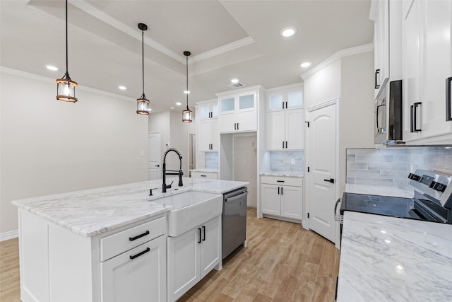 kitchen with appliances with stainless steel finishes, pendant lighting, a center island with sink, light hardwood / wood-style floors, and white cabinetry