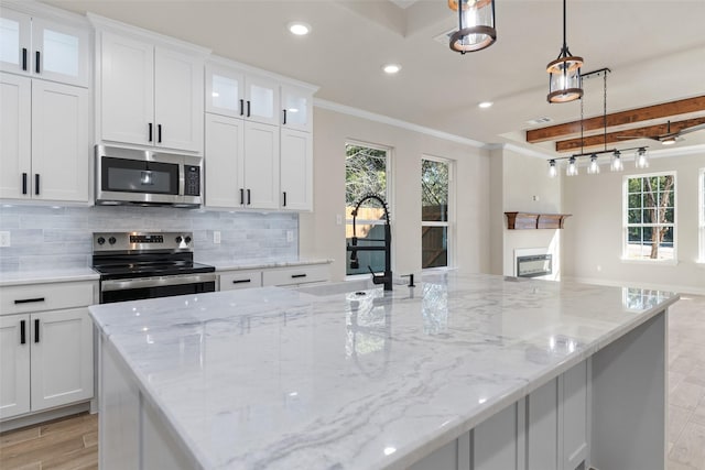 kitchen featuring appliances with stainless steel finishes, white cabinetry, a wealth of natural light, and pendant lighting