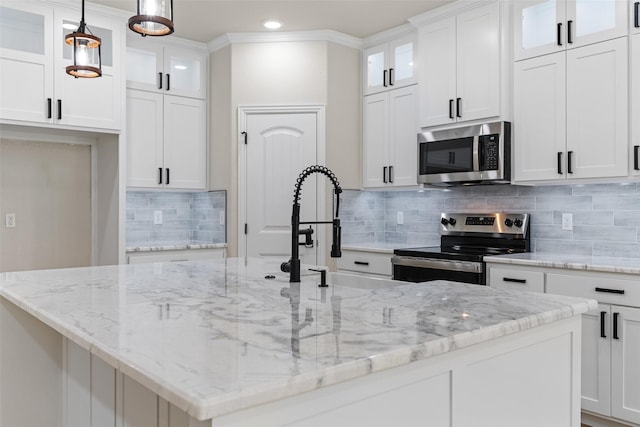 kitchen with white cabinets, decorative light fixtures, stainless steel appliances, and a kitchen island with sink