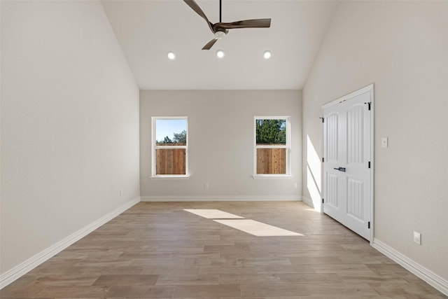 spare room featuring light wood-type flooring, high vaulted ceiling, and ceiling fan