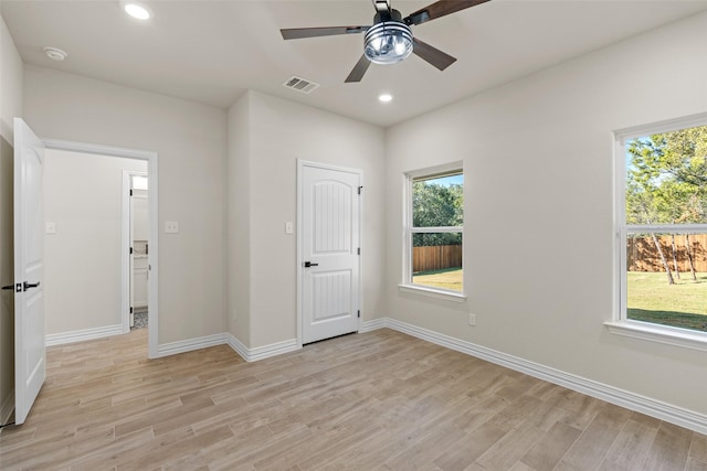 unfurnished bedroom featuring multiple windows, ceiling fan, and light wood-type flooring