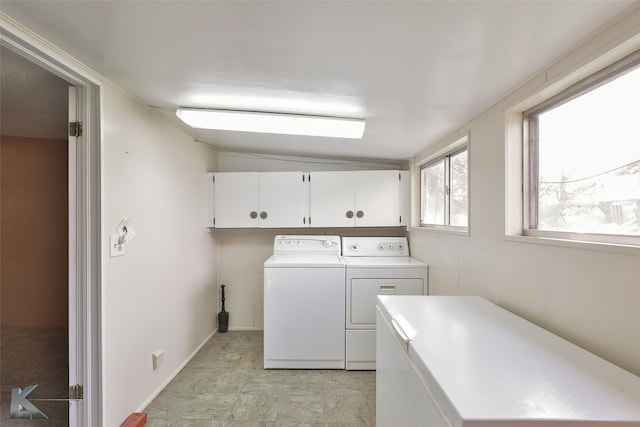 clothes washing area featuring cabinets and washer and clothes dryer