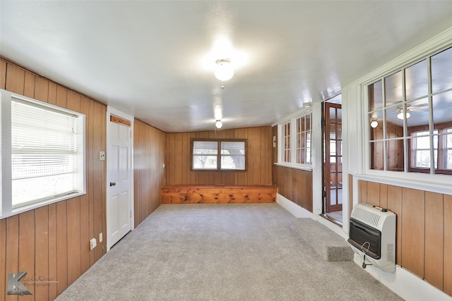 unfurnished room with wooden walls, carpet floors, heating unit, and a wood stove