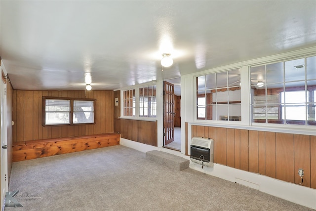 unfurnished living room featuring wooden walls, carpet flooring, and heating unit