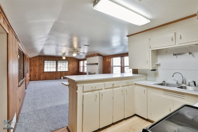 kitchen with lofted ceiling, sink, ceiling fan, wooden walls, and kitchen peninsula