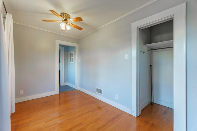 unfurnished bedroom with a closet, ceiling fan, hardwood / wood-style floors, and crown molding