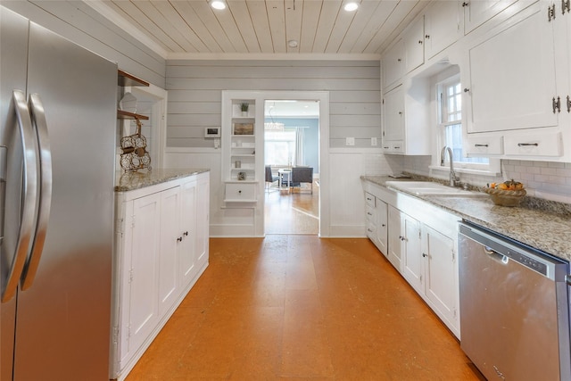 kitchen featuring light stone countertops, appliances with stainless steel finishes, backsplash, sink, and white cabinetry