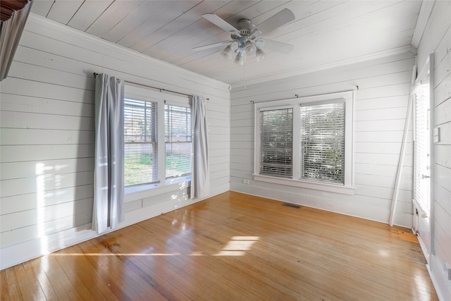 unfurnished room featuring wood walls, light hardwood / wood-style flooring, ceiling fan, and wood ceiling