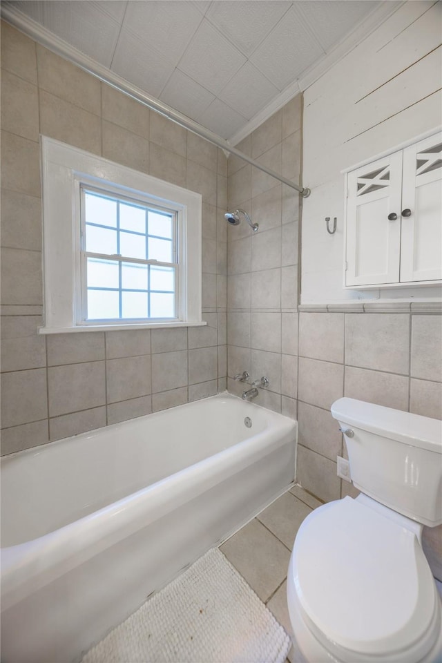 bathroom with tiled shower / bath combo, crown molding, tile walls, tile patterned flooring, and toilet