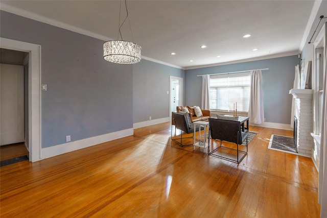 dining area featuring crown molding, a fireplace, a chandelier, and hardwood / wood-style flooring