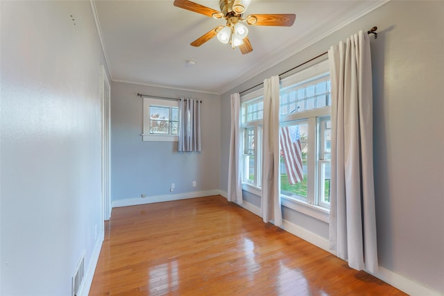 unfurnished room with ornamental molding, light wood-type flooring, ceiling fan, and a healthy amount of sunlight