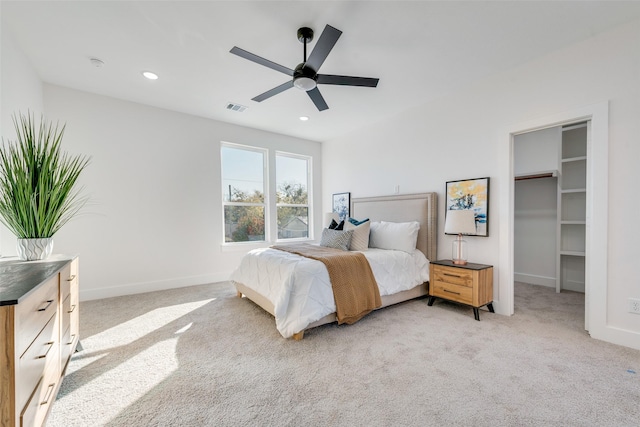 carpeted bedroom featuring a walk in closet and ceiling fan