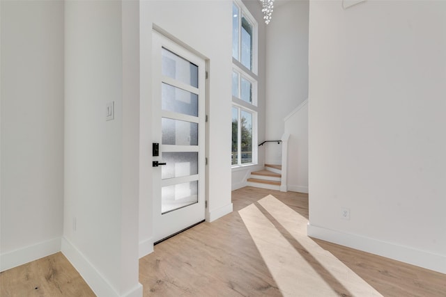 foyer entrance featuring a towering ceiling and light hardwood / wood-style floors