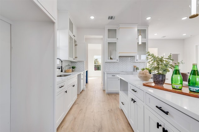 kitchen featuring decorative backsplash, white cabinetry, sink, and light hardwood / wood-style floors