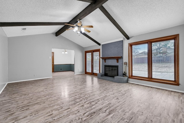 unfurnished living room with lofted ceiling with beams, wood-type flooring, a fireplace, and ceiling fan with notable chandelier