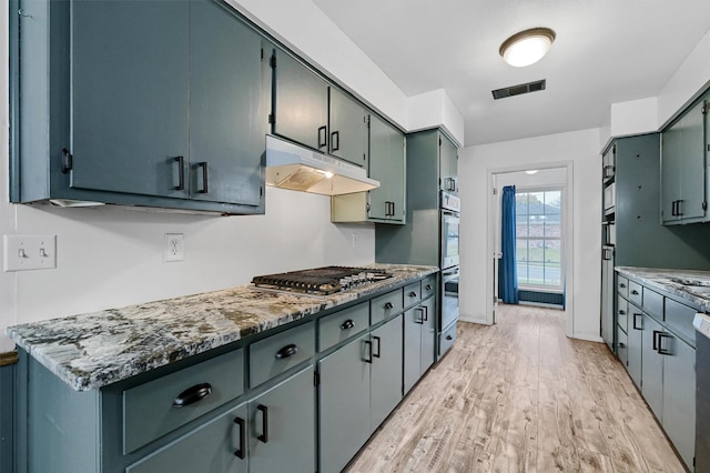 kitchen featuring light hardwood / wood-style flooring, stainless steel appliances, and dark stone counters