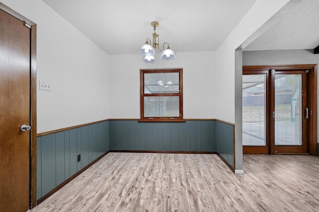 empty room with a notable chandelier and light hardwood / wood-style flooring