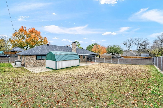 rear view of property featuring a shed, a yard, and a patio