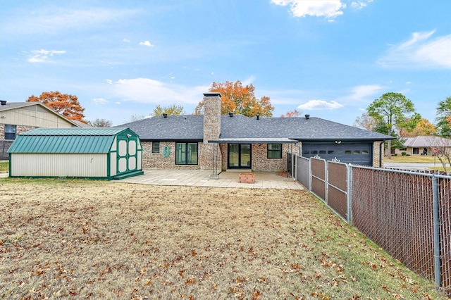 rear view of property with a storage unit, a yard, and a patio area