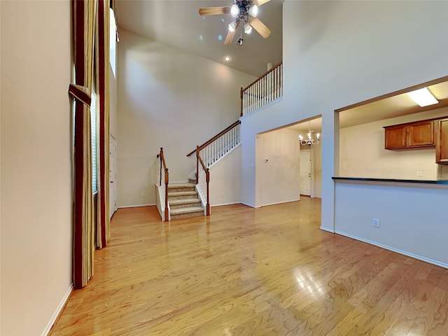 4133 Kyndra Cir, Richardson, TX 75082 - unfurnished living room with stairway, baseboards, light wood-type flooring, a towering ceiling, and ceiling fan with notable chandelier