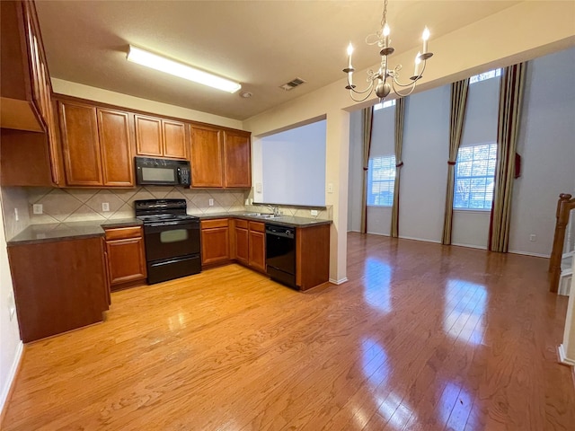 kitchen with an inviting chandelier, black appliances, sink, decorative backsplash, and light hardwood / wood-style floors