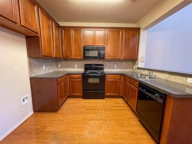 kitchen featuring sink, decorative backsplash, light hardwood / wood-style flooring, and black appliances