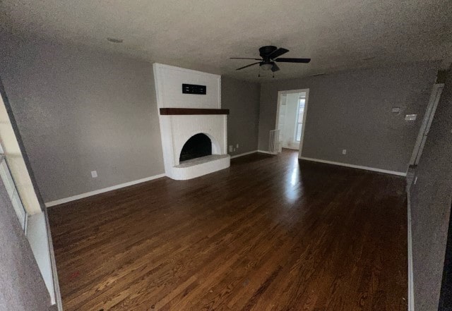 unfurnished living room with a textured ceiling, ceiling fan, and dark wood-type flooring