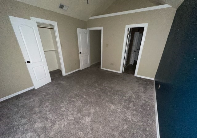 unfurnished bedroom featuring dark carpet, crown molding, a closet, and vaulted ceiling