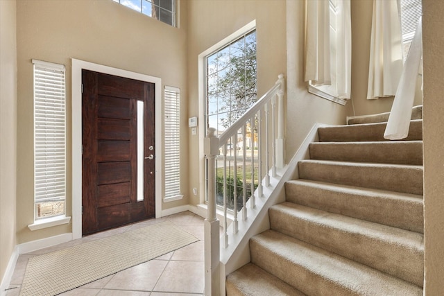 foyer entrance with a wealth of natural light, light tile patterned floors, and a high ceiling